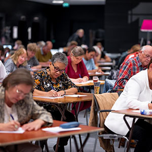 mensen zitten aan tafels te schrijven