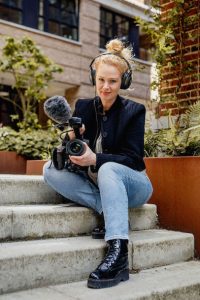 Documentairemaakster Sara Blom zit met camera op een trap