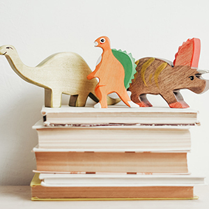 stapel kinderboeken met dinosaurierpoppen erop